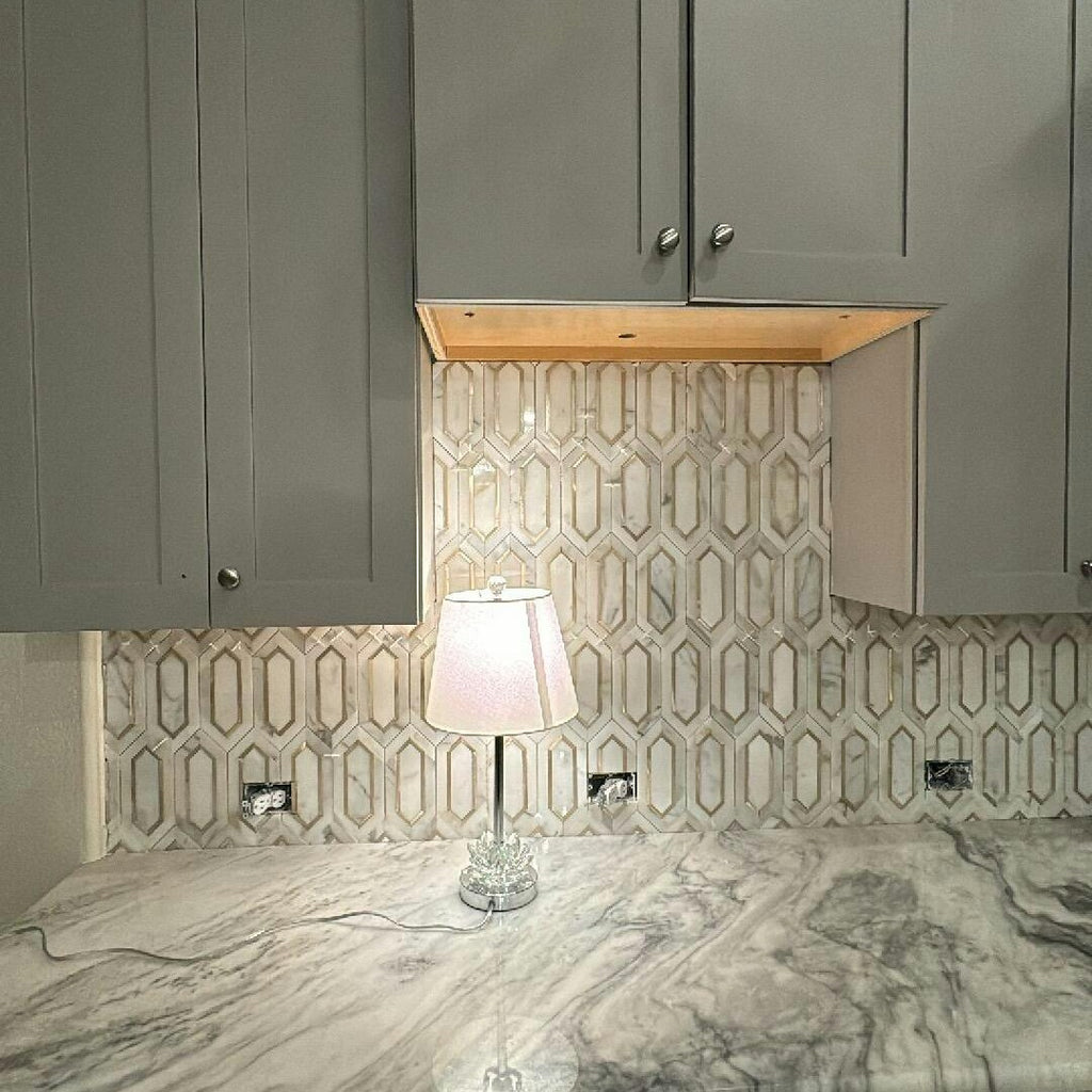 Closeup of Grey Kitchen Cabinets and White and Gold Picket Tile Backsplash Illuminated by Small Lamp on Marbled Countertop