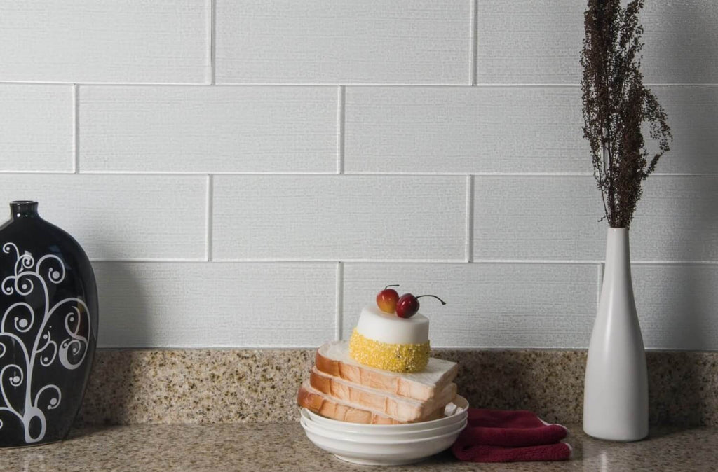 Textured White Glass Subway Tile Kitchen Backsplash Behind Speckled Countertop with Vases and Plates of Food