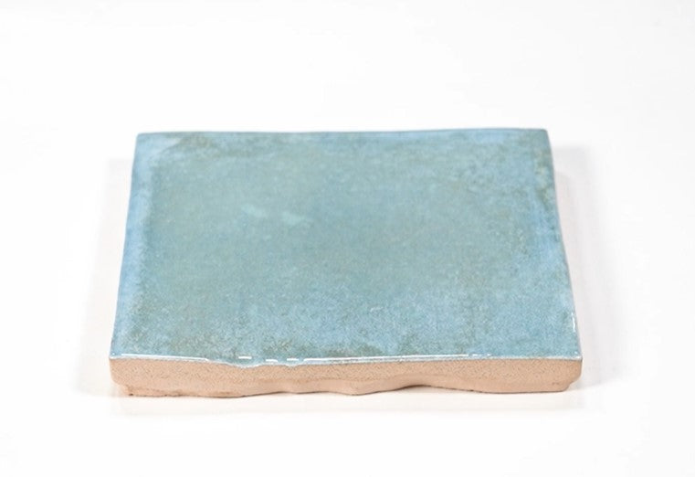 Closeup of a single pale aquamarine blue-green square ceramic tile.